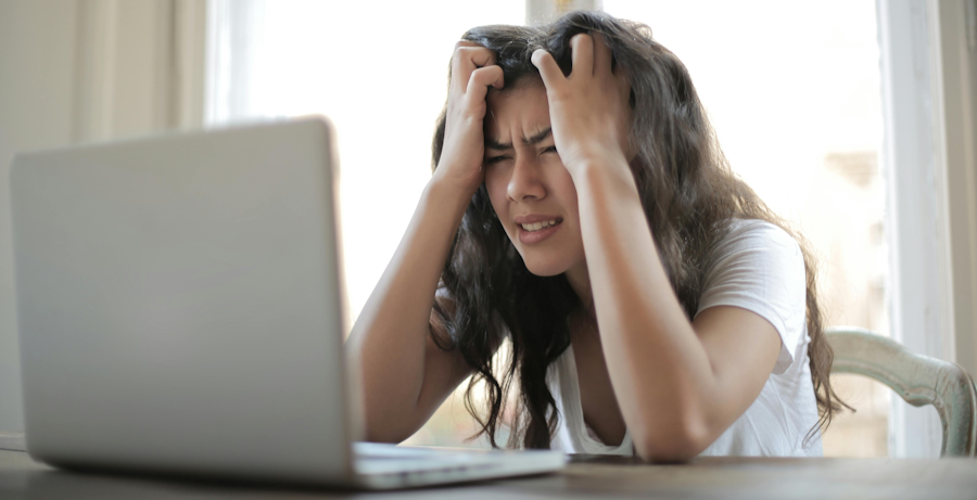 Mujer joven con cara de frustración al ver la pantalla de su portátil